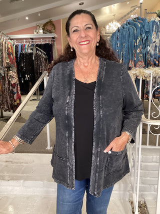 Woman wearing a dark black denim jacket in a clothing store.