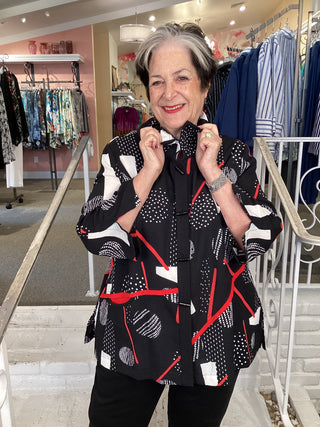 Woman wearing a black and red patterned dress in a clothing store.